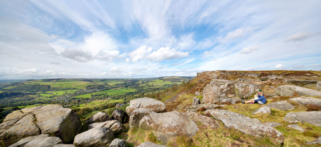 Curber Edge in Derbyshire couple on hill top looking out over sweeping landscape with beautiful cloud formation