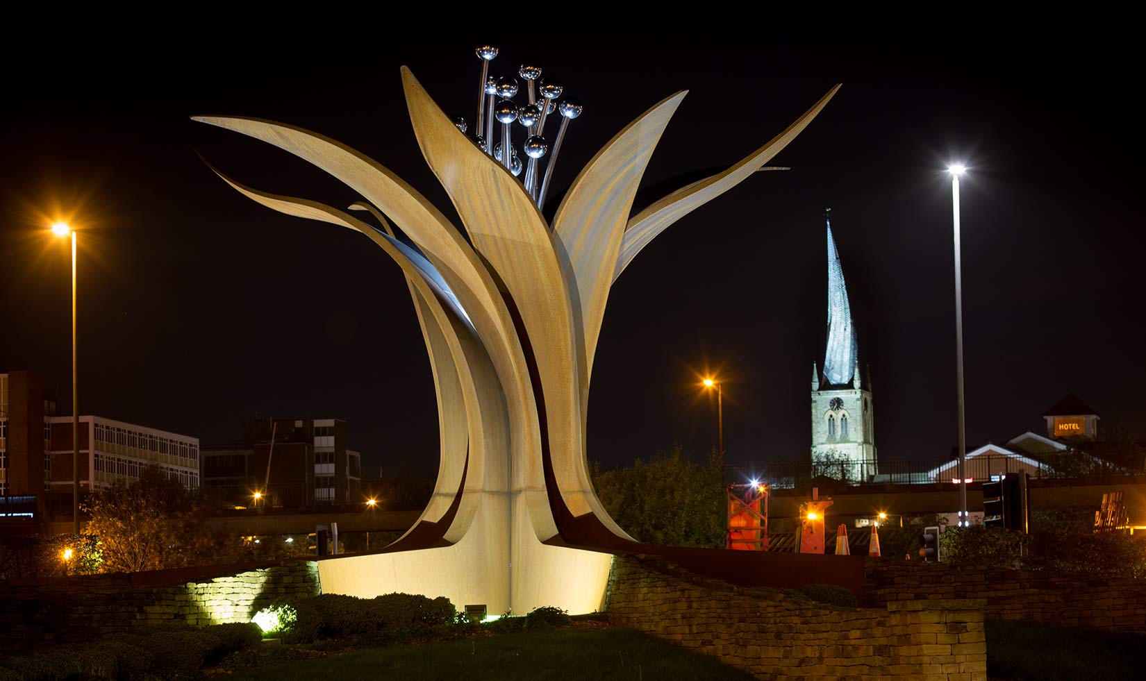 Destination Marketing Photography The growth Sculpture in chesterfield, Derbyshire with the crooked spire in the background to the right. Shot at nigh both are lit with lights