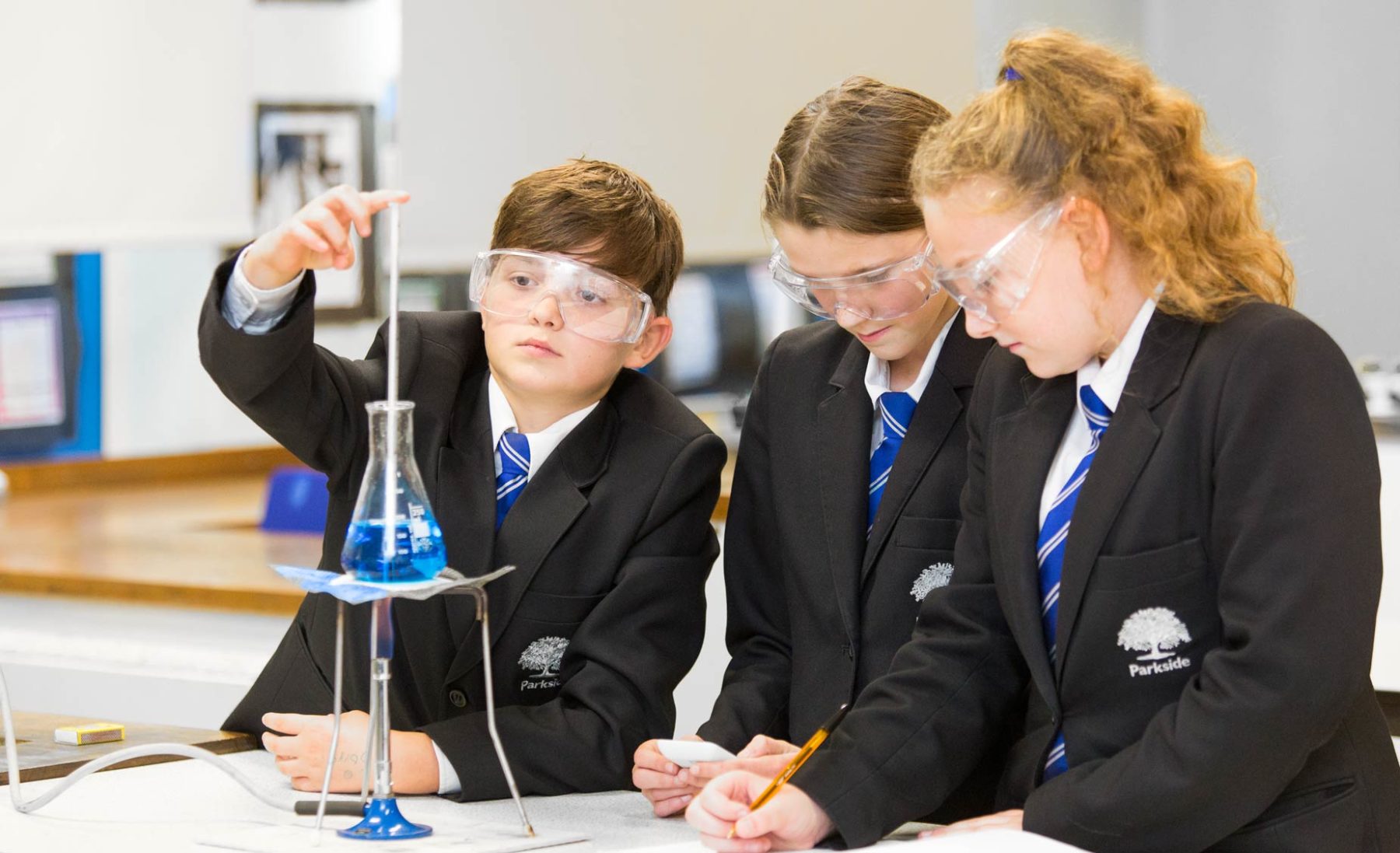 Three children in school uniform doing science experiment in class