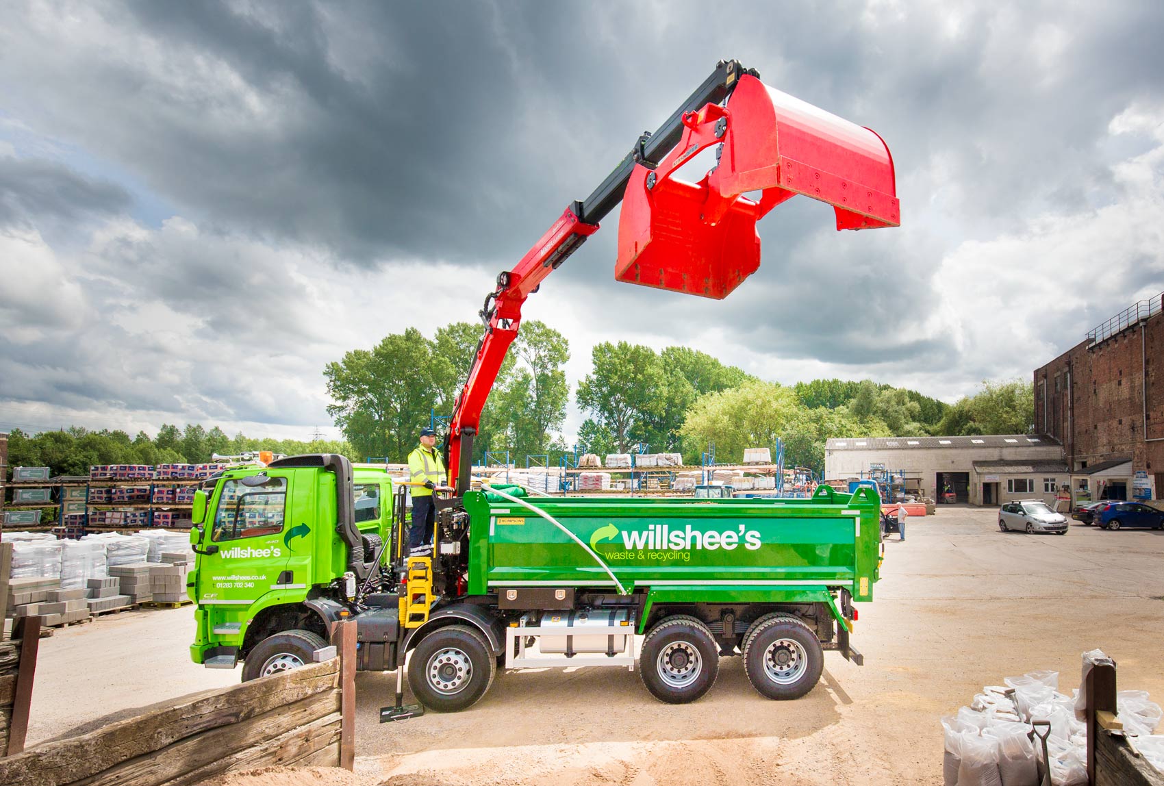 A commercial photography Sheffield shot of a green Grab truck with bright red granner in builders yard with a moody grey sky