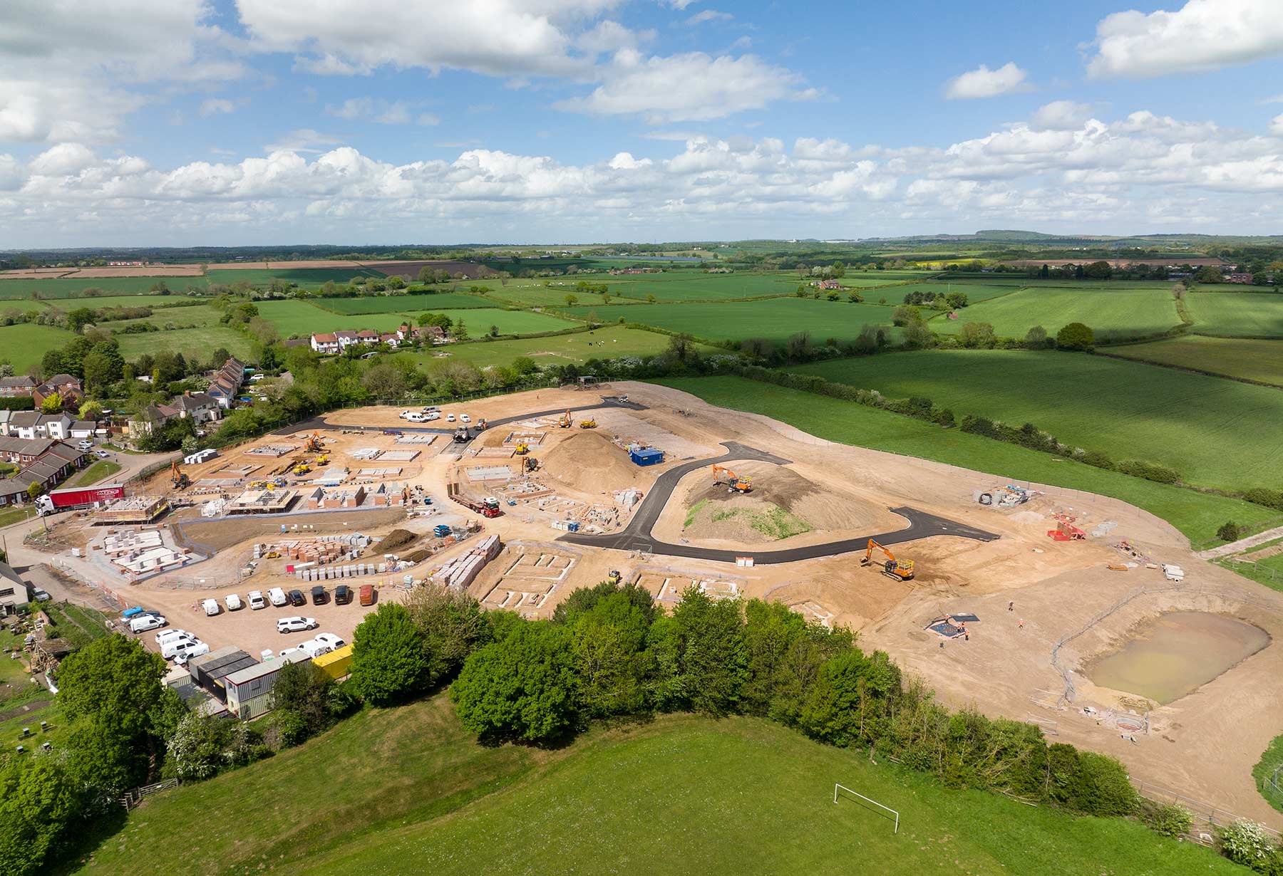 A photograph of the Groundworks phase of a housing development construction project. Showing the whole site partial roadways an building plot foundations