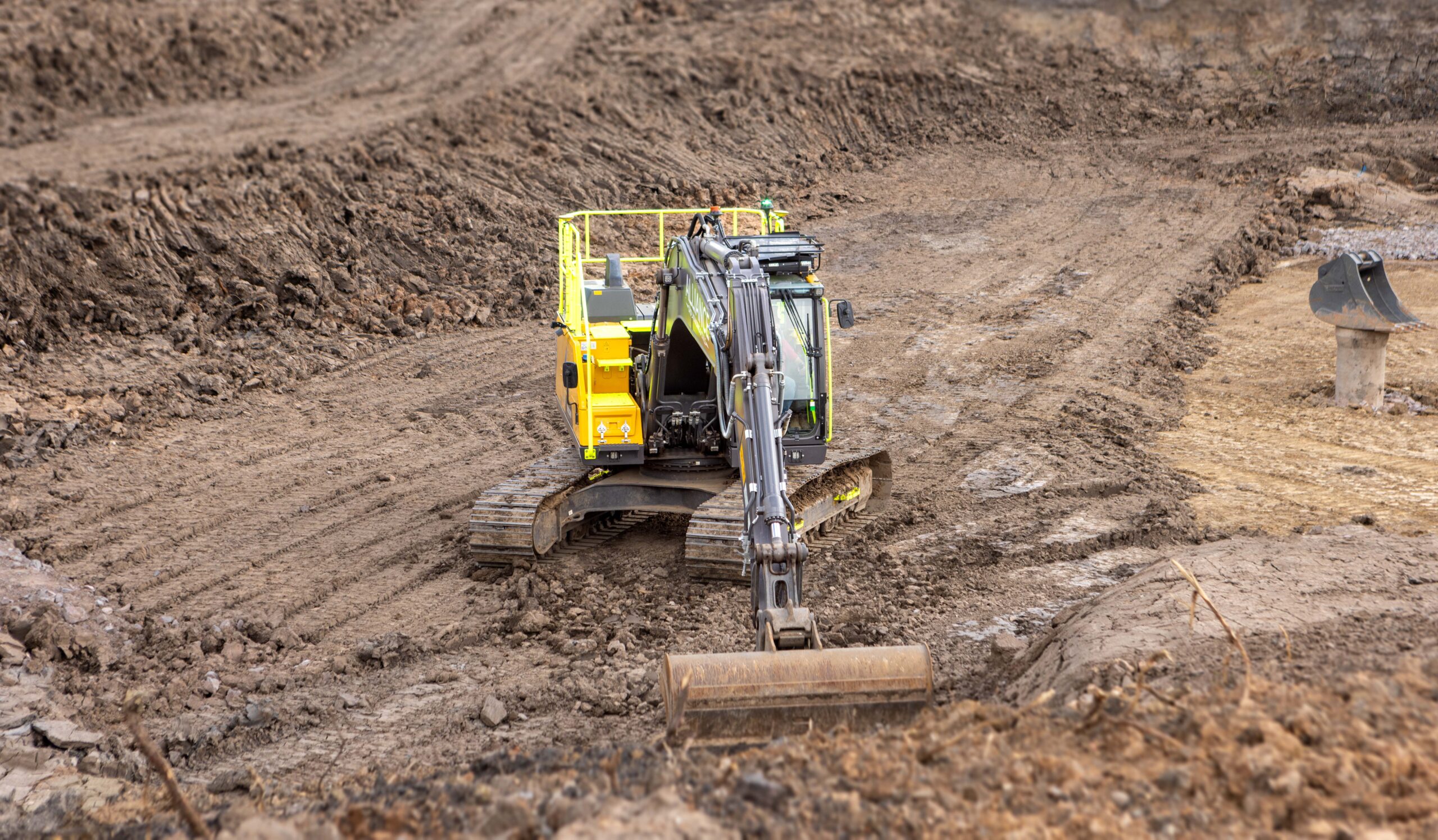 A yellow Volvo EC220E medium crawler excavators during groundworks operations.