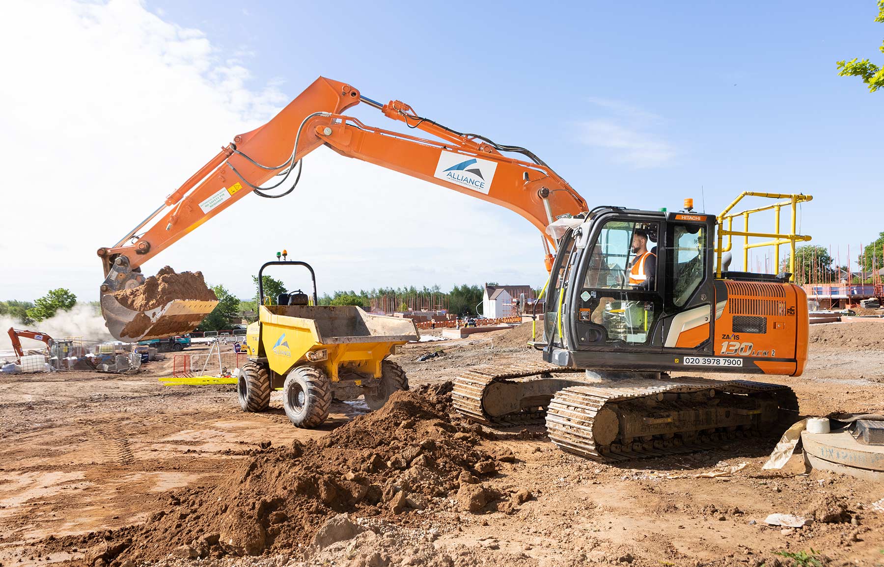 Plant Machinery, an orange Hitachi Xaxis 130 excavator loading a Medcalac TA9 dumper truck on a construction site with brown earth and a blue sky