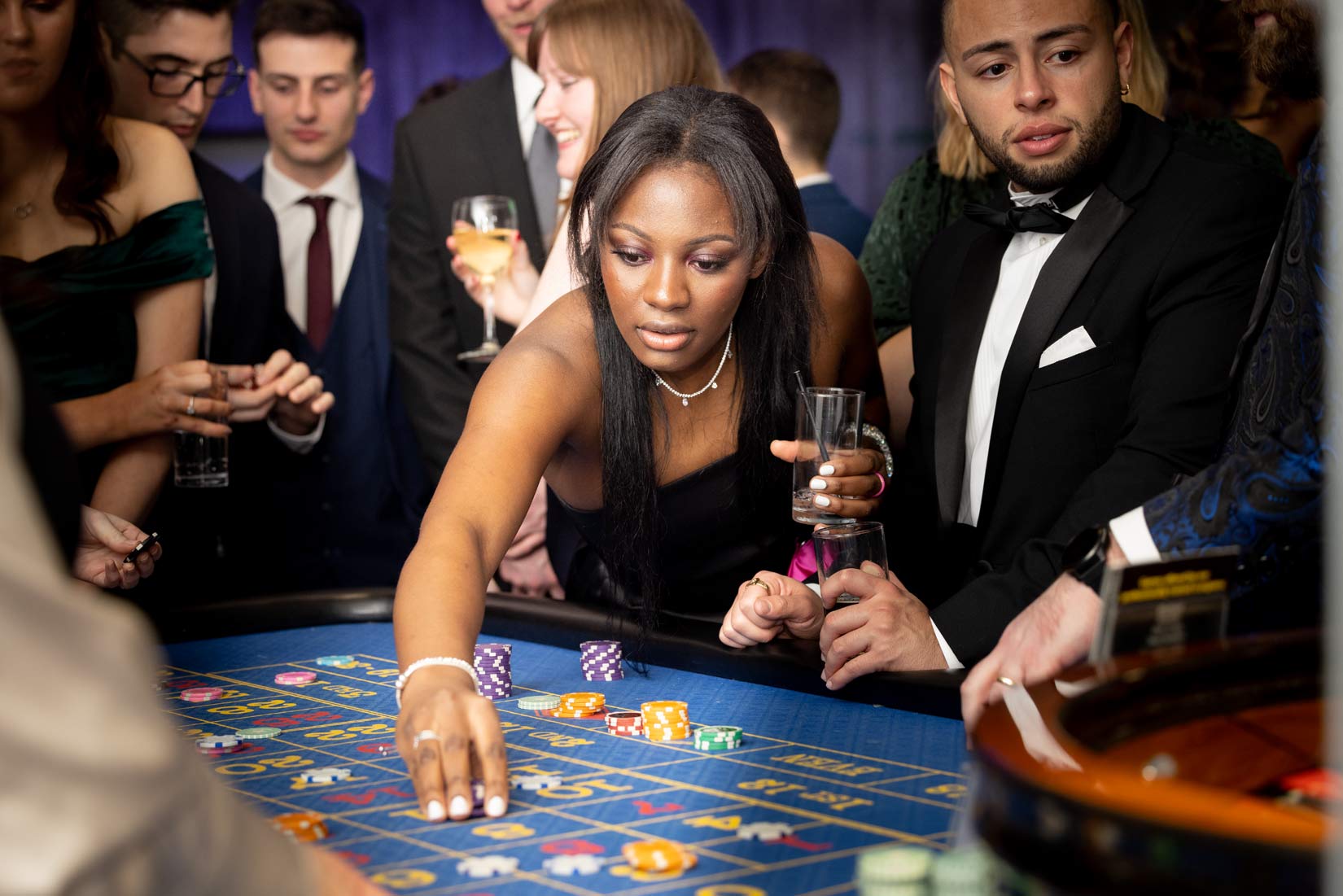Young lady places a bet on a blue roulette table at at an awards ceremony. 
