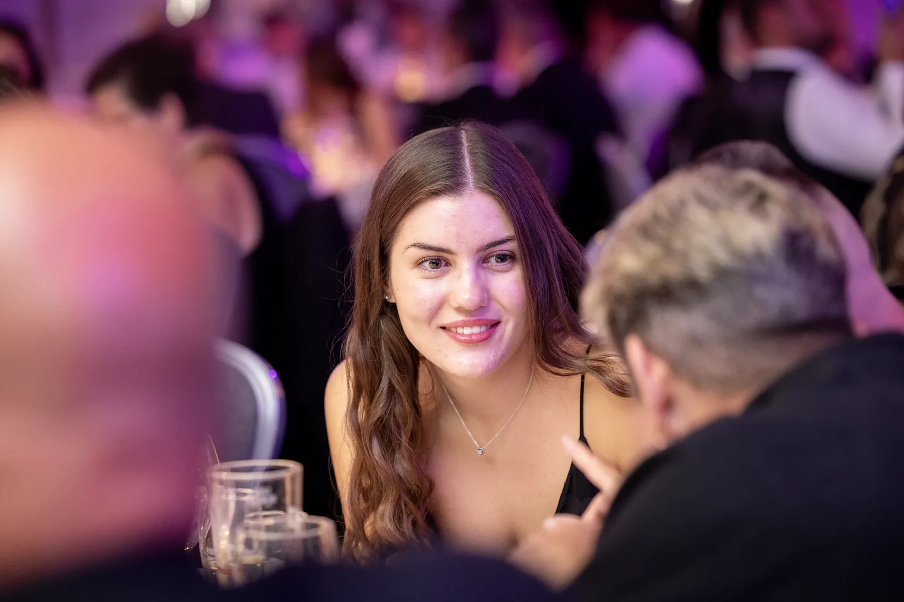 Young woman engaged in animated conversation at a table during a Manchester gala dinner.